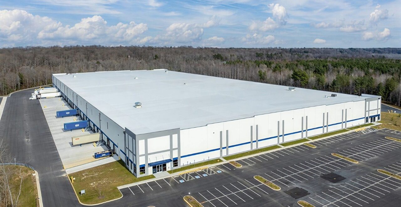 Exterior aerial view of a large industrial warehouse building with parking and loading docks.