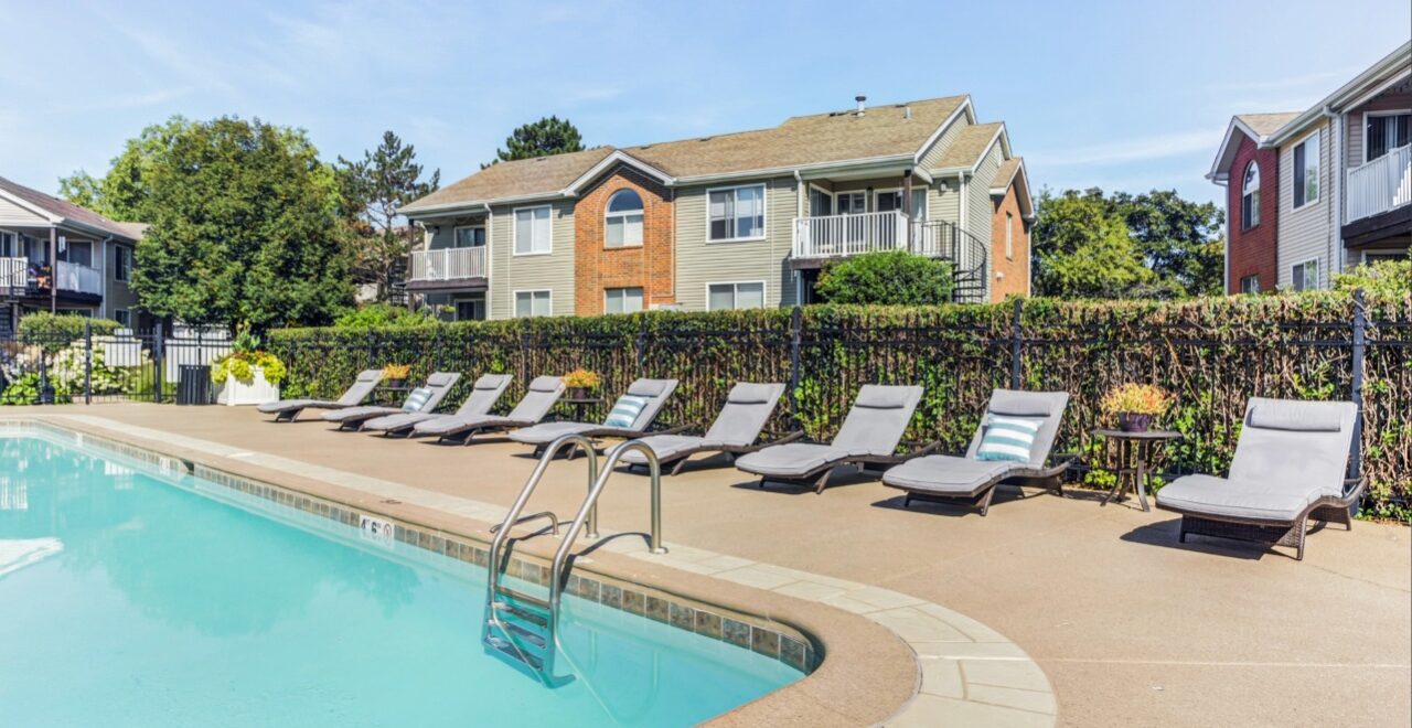 Swimming pool with lounge chairs and landscaped grounds at Ashford at Geneva, a multifamily apartment community in Geneva, Illinois.