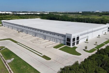 Aerial view of a modern industrial distribution facility with loading docks, truck courts, and surrounding green space.